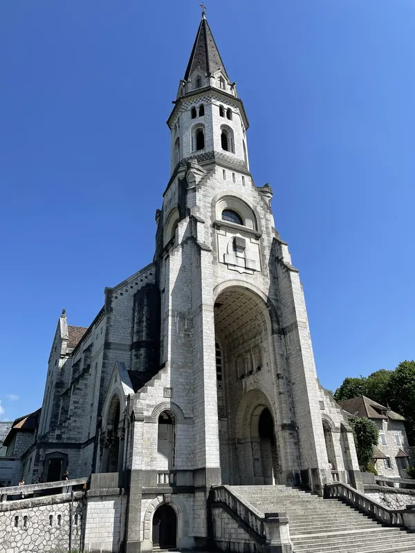 A white stone basilica with a tall bell tower against a deep blue sky