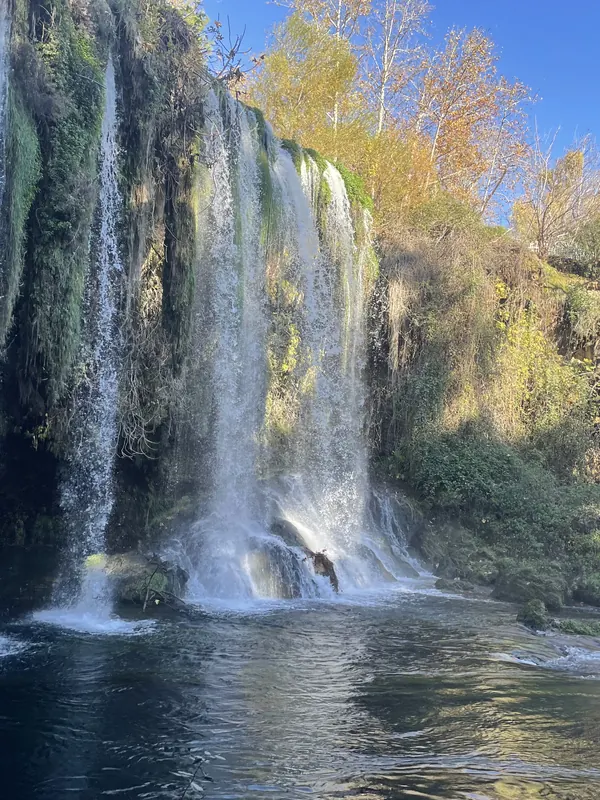 Curtains of water pouring over a mossy cliff at the Düden Waterfalls, framed by autumn trees