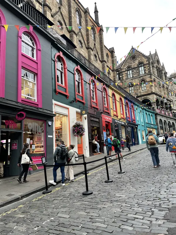 Brightly painted shopfronts in pink, blue and green along curving, cobbled Victoria Street