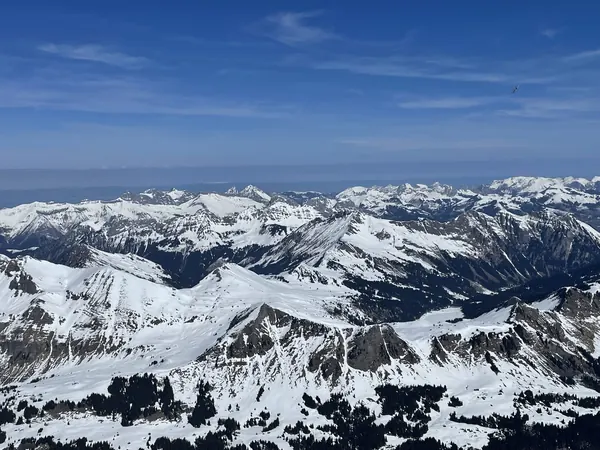 A panorama of snow-covered Alpine ridges under a clear blue sky