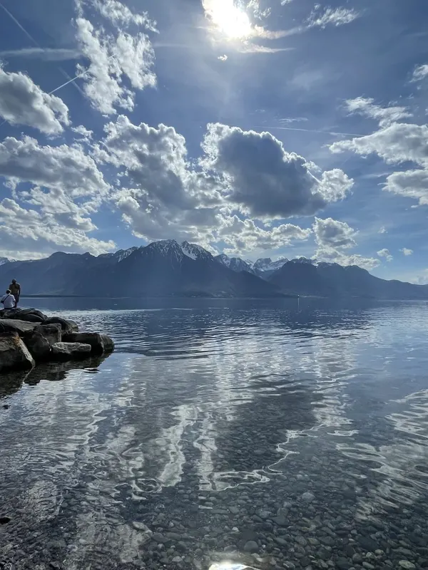 Clouds reflected in the calm water of Lake Geneva at Montreux, with mountains across the lake