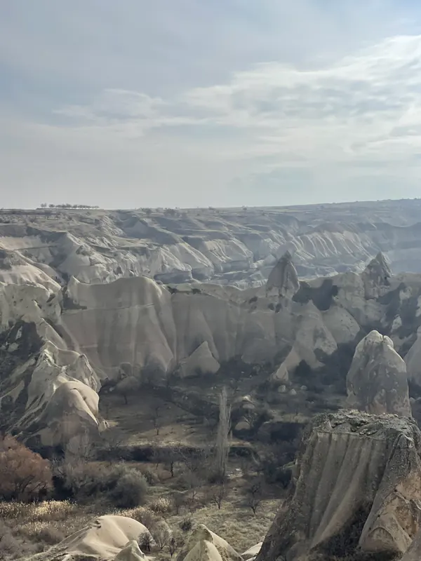 Pale cone-shaped rock formations filling a valley under a hazy sky