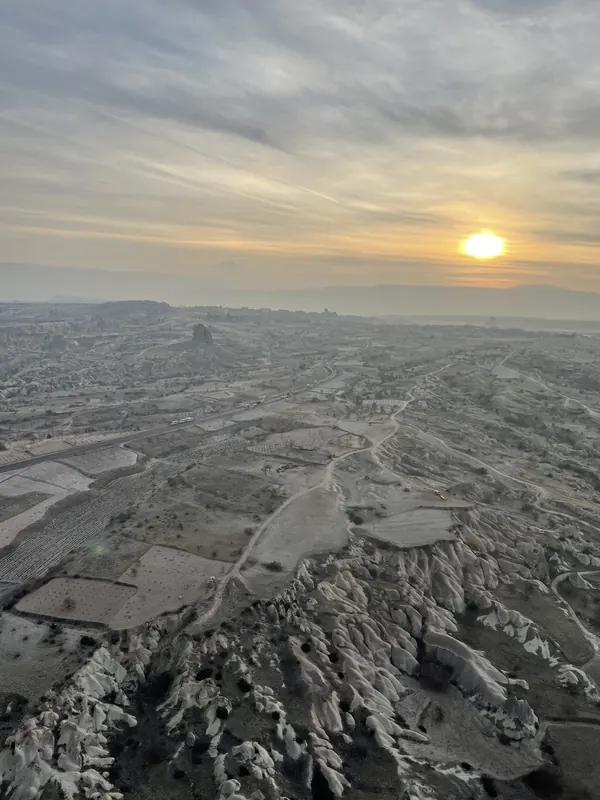 The sun rising over ridged valleys and fields, seen from high above