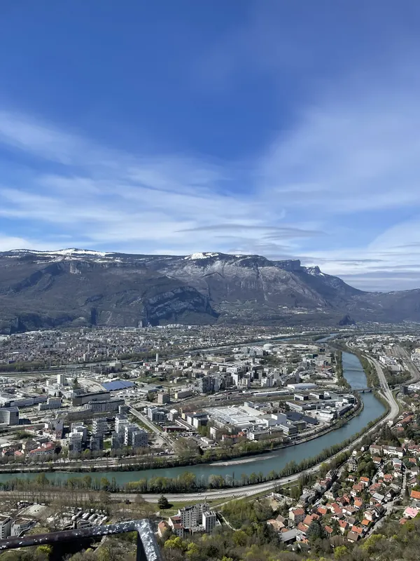 The Isère river curving through Grenoble below a long limestone ridge, seen from the Bastille