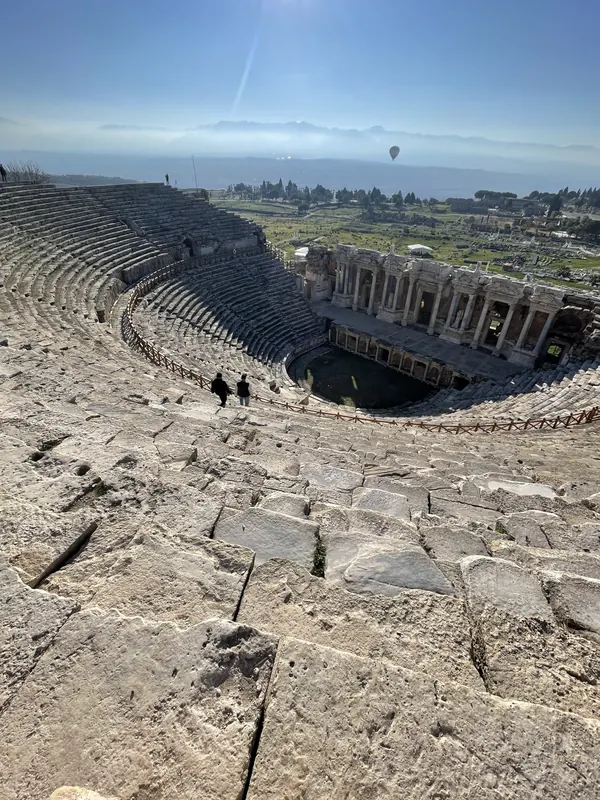 Rows of ancient stone seats curving down to the stage of the Roman theatre at Hierapolis