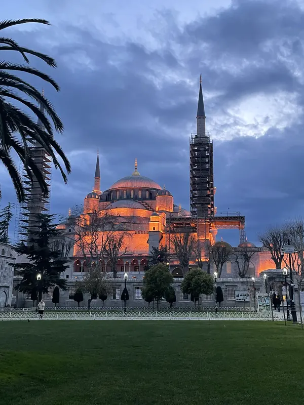 The domes and minarets of the Blue Mosque glowing against a stormy evening sky