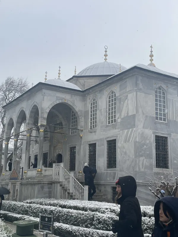 A white marble pavilion at Topkapı Palace with snow on the hedges in front