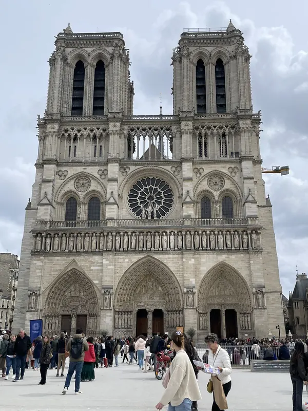 The twin towers and west front of Notre-Dame cathedral under a cloudy sky