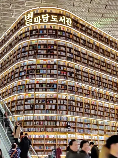 Towering curved bookshelves lit from within at the Starfield Library in Seoul