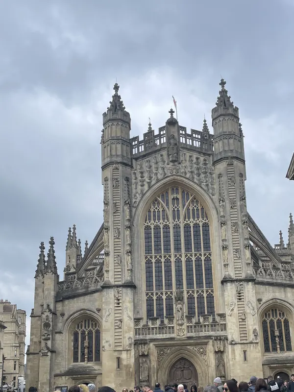 The tall Gothic west front of Bath Abbey with its great window, under a grey sky