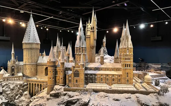 The detailed scale model of Hogwarts castle, its towers and rooftops dusted with snow, lit by spotlights